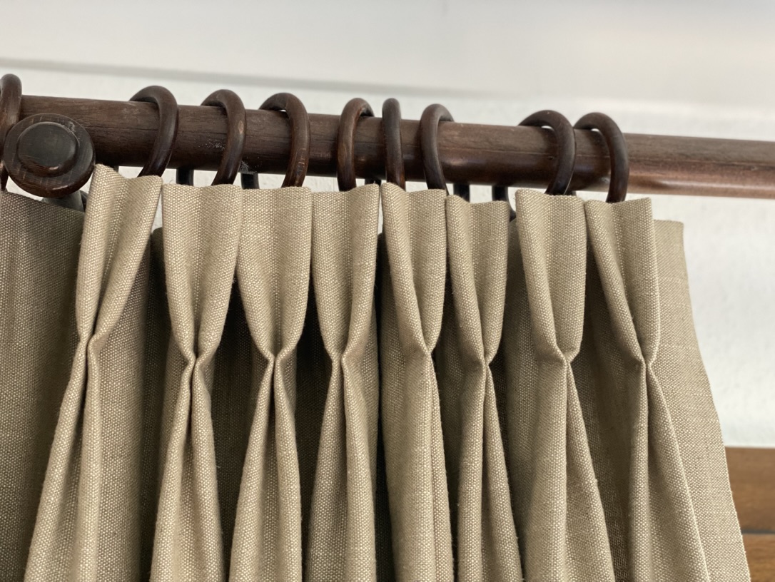 Détail de plis pincés en lin naturel sur tringle bois et anneaux — atelier Maison Esclavissat